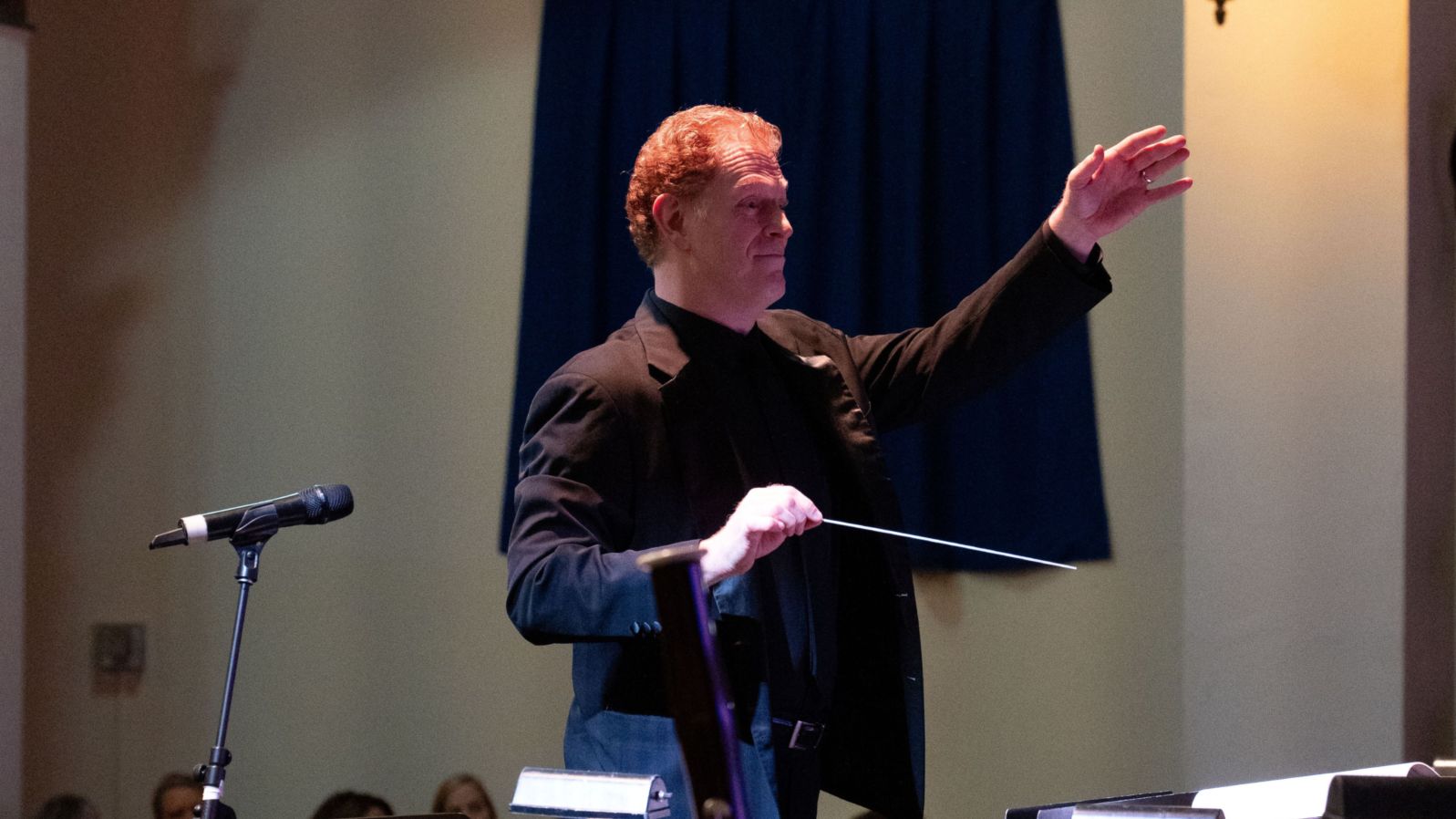 photograph of Rick Lowe, conductor of the Palatine Concert Band in mid-performance with arms raised.